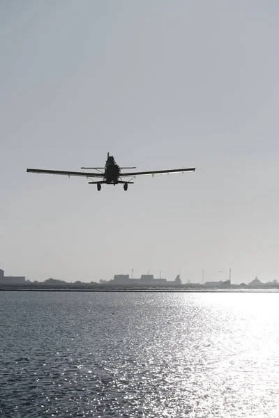 老式单引擎飞机与螺旋桨在湖面上飞行的侧影的垂直照片 — 图库照片