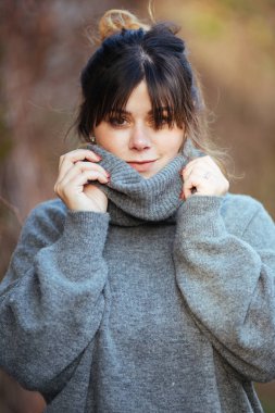 A vertical selective focus shot of a young lady wearing a gray turtleneck sweater clipart