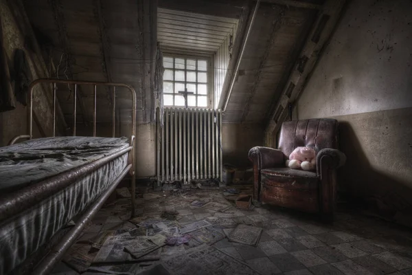 A ruined bedroom with an old bed and a leather armchair of an abandoned house