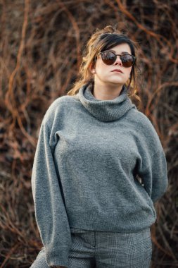 A vertical shot of a young lady wearing a gray turtleneck sweater and sunglasses clipart