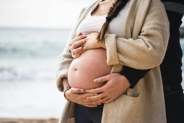 夫に抱かれた妊娠中の女性の裸の腹の美しい切り取られたイメージ — ストック写真