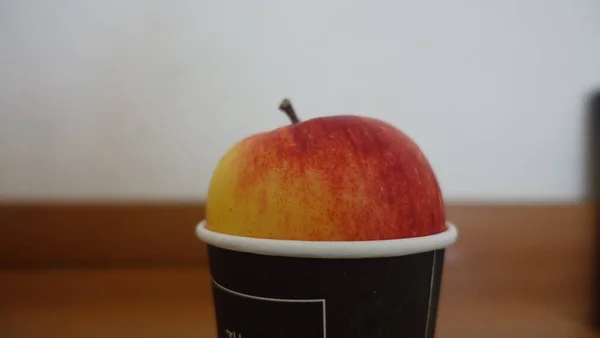 Μια Επιλεκτική Εστίαση Closeup Ενός Μήλου Ένα Φλιτζάνι Στο Τραπέζι — Φωτογραφία Αρχείου