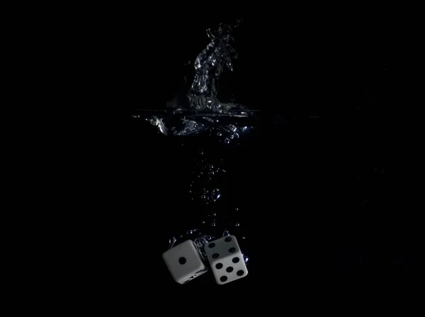 特写骰子掉进水中的特写镜头 背景是黑色的 — 图库照片