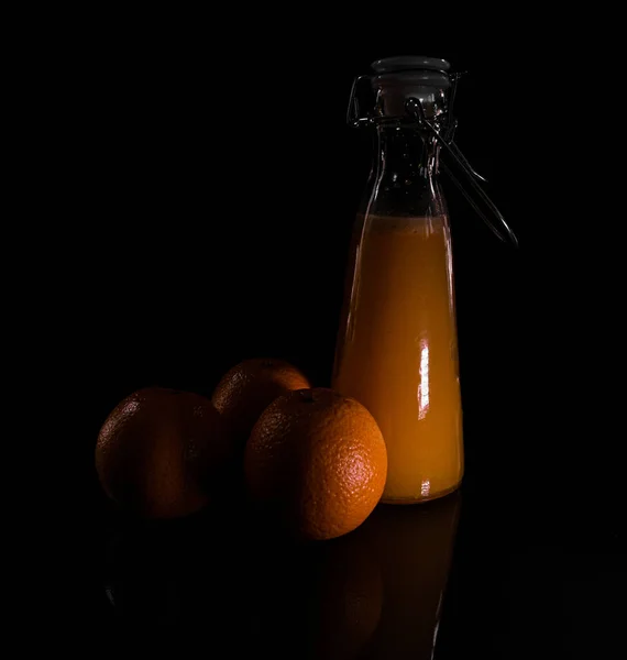 Närbild Apelsiner Och Flaska Färsk Juice Isolerad Svart Bakgrund Skuggorna — Stockfoto