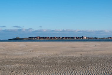A beautiful beach at the coast of the East Frisian Island Norderney with houses in the background clipart