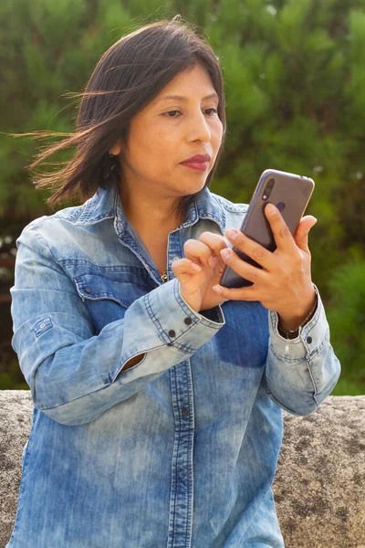 A vertical shot of a Hispanic female gazing at her phone
