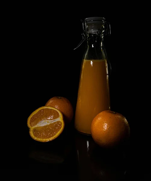 Disparo Vertical Naranjas Una Botella Jugo Aislado Sobre Fondo Negro — Foto de Stock