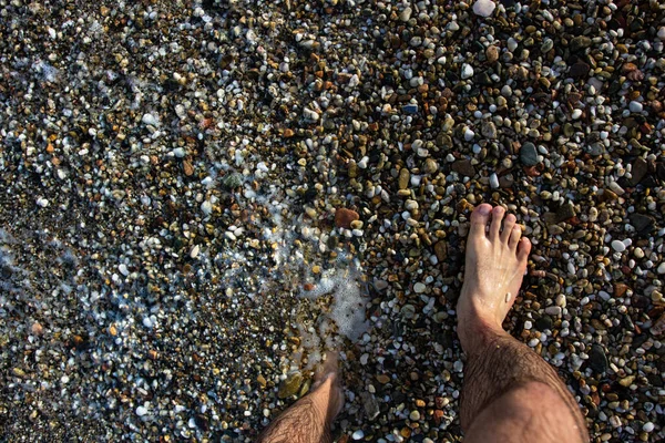 Sahilde Çakıl Taşlarıyla Kaplanmış Bir Adamın Ayakları Sahilde Terapi Amaçlı — Stok fotoğraf