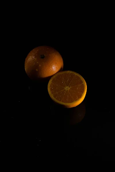 Colpo Verticale Taglio Bagnato Metà Arancione Suo Riflesso Sfondo Nero — Foto Stock