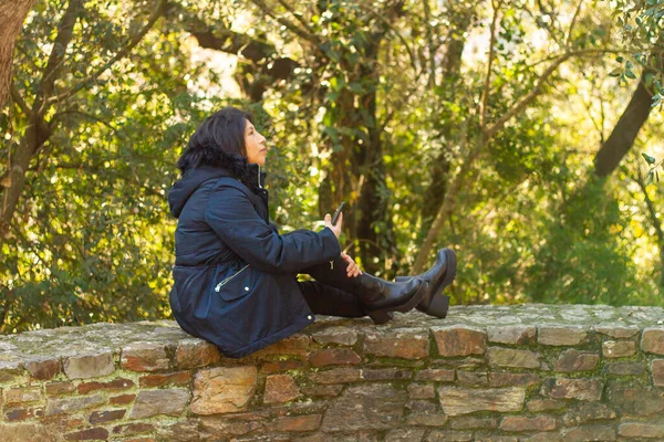 Eine Junge Hispanische Frau Mantel Sitzt Auf Einer Steinmauer Während — Stockfoto