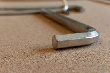 A selective focus closeup of an Allen key on a wooden surface clipart