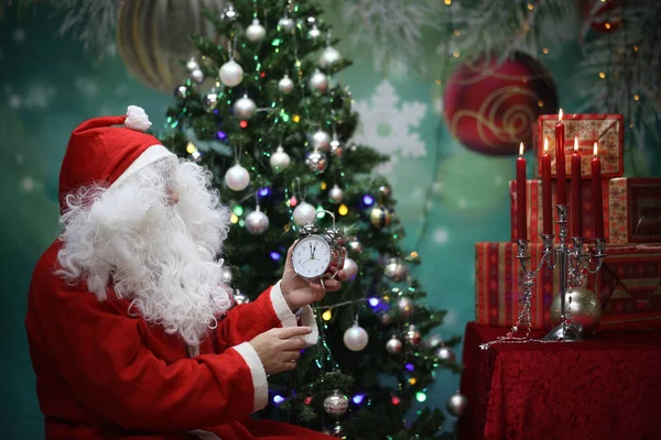 Santa Claus Sitting Festive New Year Tree Holding Silver Clock — Stock Photo, Image