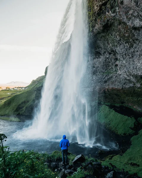 アイスランドの岩場に囲まれた滝の美しい景色を楽しむ孤独な人 — ストック写真