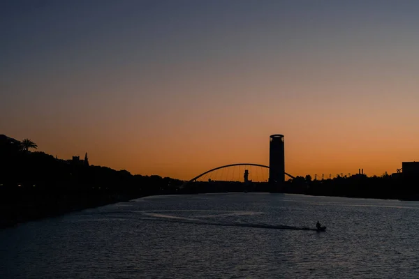 在美丽的夕阳西下 一个男人在平静的海湾里钓鱼的照片 — 图库照片