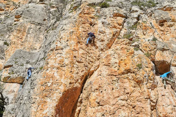 赤い山の壁にハーネスを持つ3人の登山者の低角度ショット — ストック写真
