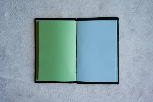 白い背景に緑と青のシートが隔離された開いたノートブックのトップビュー — ストック写真