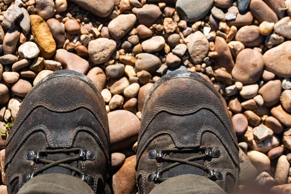 Güneş Işığında Çakıl Taşlarının Üzerinde Duran Insan Ayaklarının Üst Görüntüsü — Stok fotoğraf