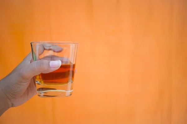 Une Main Tenant Verre Whisky Sur Fond Orange — Photo