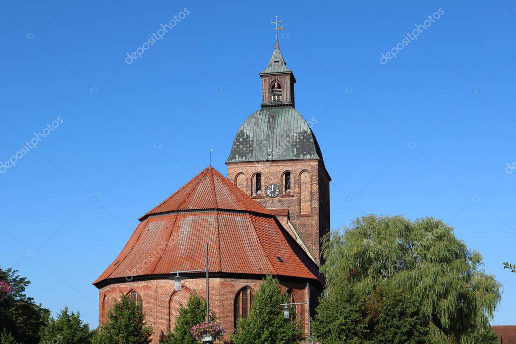 La Marienkirche Ribnitz rodeada de árboles bajo un cielo azul y la luz
