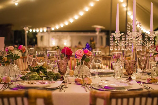 精致的餐桌布置 花朵五彩缤纷 背景为婚宴设计装饰灯饰 — 图库照片