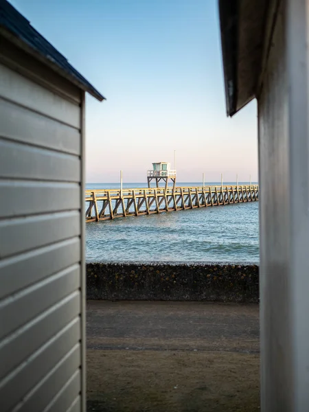 壁の間から撮影された海岸の木製の桟橋の垂直ショット — ストック写真