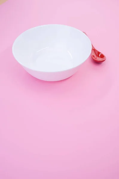 Pionowe Ujęcie Czerwonej Łyżki Obok Białej Miski Różowym Tle Ujęcia — Zdjęcie stockowe