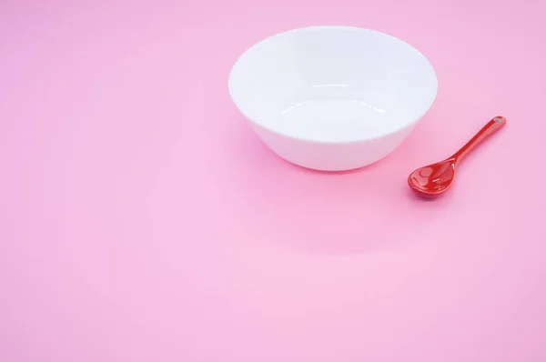 Una Cuchara Roja Colocada Junto Cuenco Blanco Sobre Fondo Rosa —  Fotos de Stock