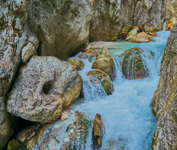 丸みを帯びた岩の間のカスケードを駆け抜ける渦巻く光の青い渓流 — ストック写真