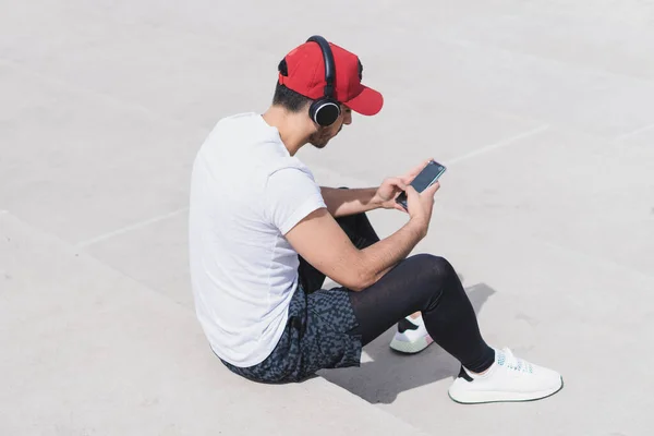 Joven Deportista Con Auriculares Sentado Calle Mirando Teléfono — Foto de Stock