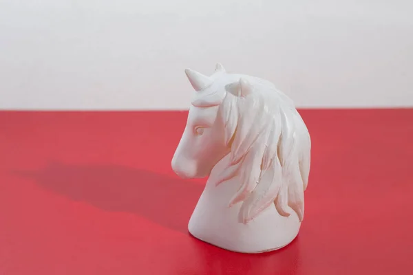 Tiro Close Uma Estatueta Cabeça Cavalo Branco Uma Superfície Vermelha — Fotografia de Stock