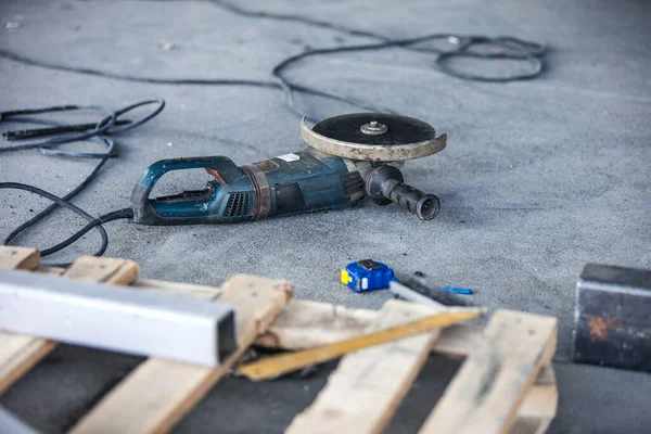 A selective focus shot of a flexible retractable measure tape and angle grinder tool at the construction site