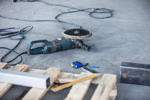 A flexible retractable measure tape and angle grinder tool, instruments at the construction site