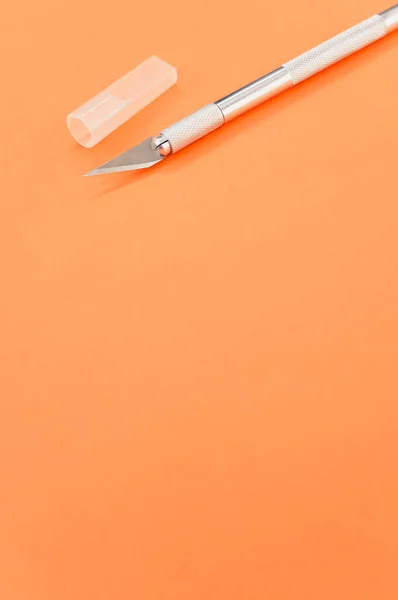 一种垂直拍摄的金属手术刀 顶部与橙色背景隔离 — 图库照片