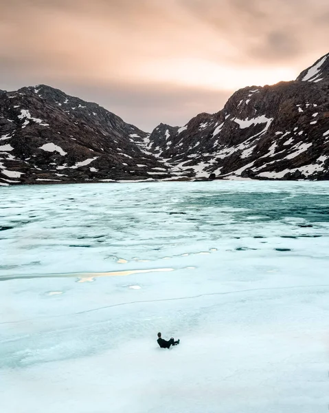 Plan Vertical Mâle Assis Sur Lac Gelé Entouré Montagnes Coucher — Photo