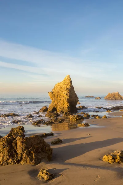 カリフォルニア州マリブの曇った空の下で輝く岩の多いエル マタドールビーチを襲う波浪の海 — ストック写真