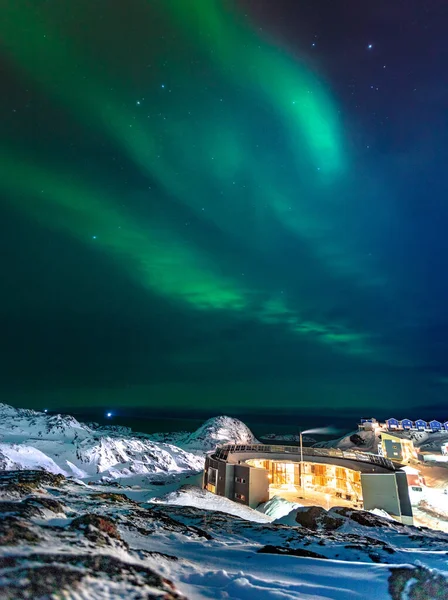 Vertikální Záběr Fascinujících Severních Světel Zasněžené Oblasti Barevnými Budovami — Stock fotografie
