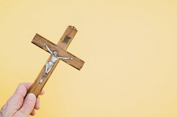 Closeup Shot Hand Holding Wooden Crucifixion Christ Cross Yellow Background — Stock Photo, Image