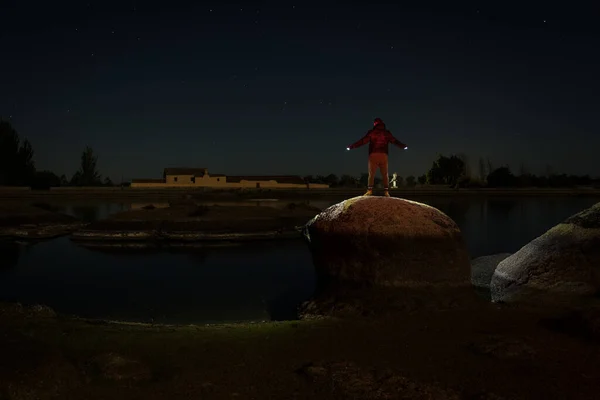 A night landscape with a person on top of a rock in the Natural Area of Los Barruecos