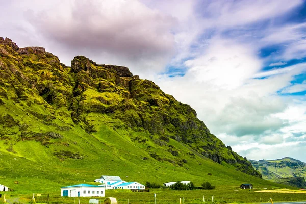 アイスランドの明るい雲の空の下で緑の山々の美しいショット — ストック写真