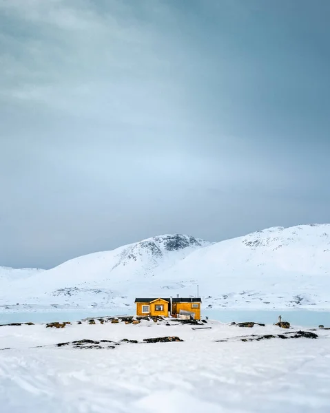 雪に覆われた山岳地帯の垂直ショットで かわいい黄色の建物 — ストック写真