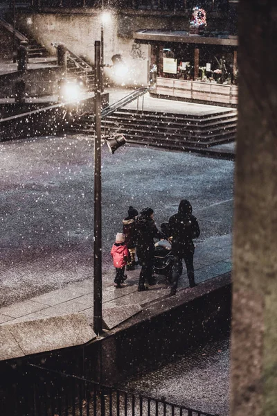 冬の雪の下で夜に路上で散歩をしている愛する家族 — ストック写真