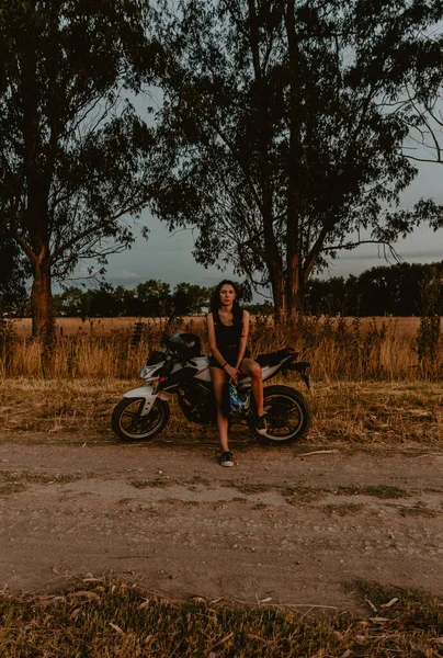 一张垂直拍摄的照片 是一个很酷的女孩骑摩托车时戴着头盔坐在沙发上 — 图库照片