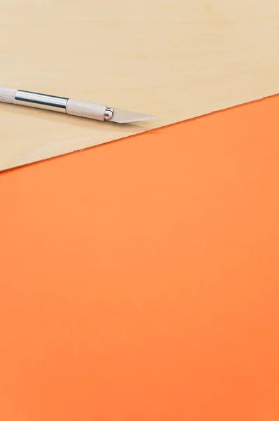 Vertikální Záběr Kovového Skalpelu Překližkovém Povrchu Izolovaném Oranžovém Pozadí — Stock fotografie