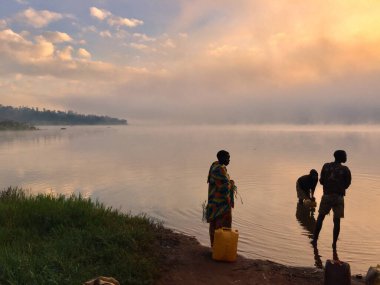 KIRUN, BURUNDI - Jun 04, 2017: Men washing up on lake shore of Lac Rwihinda in Northern Burundi clipart