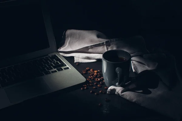从家里的概念出发 有选择性地拍摄了一台笔记本电脑 手提电脑和一杯热咖啡 周围都是豆子 — 图库照片