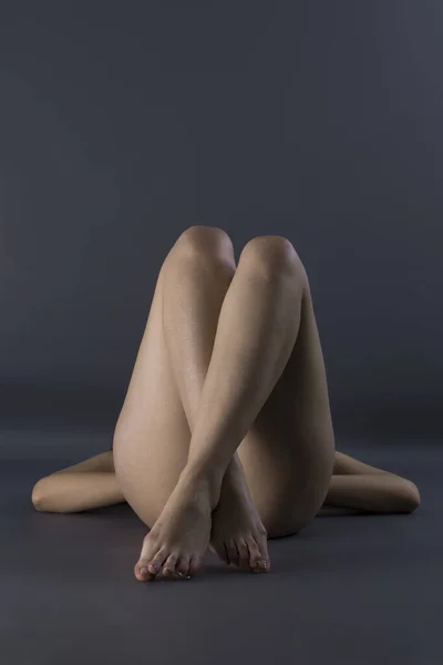 一只裸女躺在地板上蜷曲腿的垂直镜头 — 图库照片