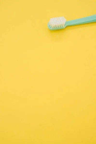 Eine Vertikale Aufnahme Einer Türkisfarbenen Zahnbürste Auf Einer Gelben Oberfläche — Stockfoto