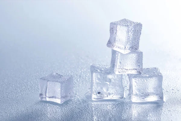 A selective focus shot of melting ice cubes on a wet surface