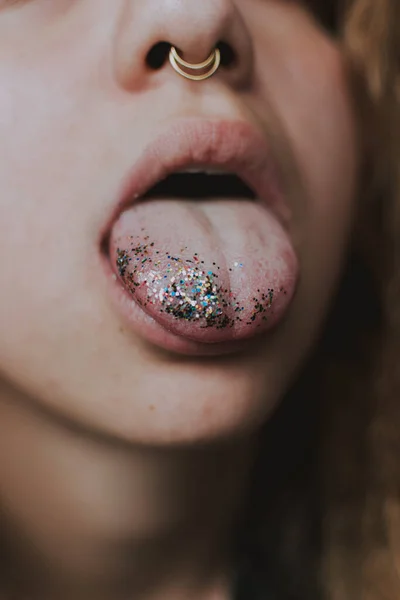 キラキラした舌を持つ女性の口の垂直ショット 最新のメイクトレンド — ストック写真