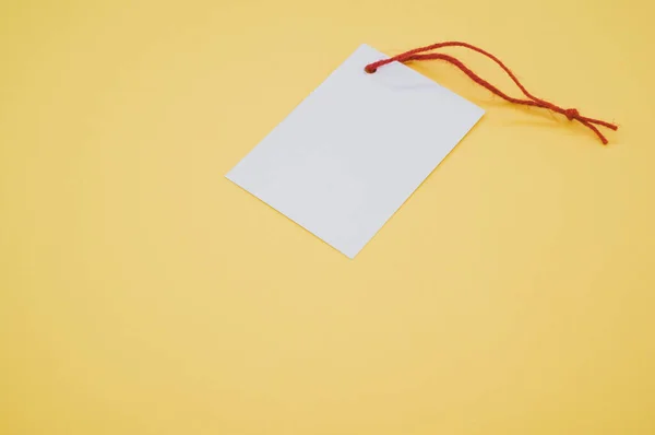 黄色の背景に赤い糸のついた白いカードのショット — ストック写真
